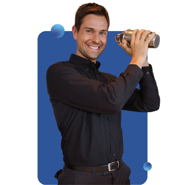 A male bartender is shaking a mixer and smiling at the viewer